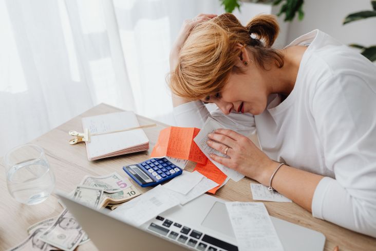Mujer preocupada revisando facturas, dinero y una calculadora ante un posible embargo de cuenta